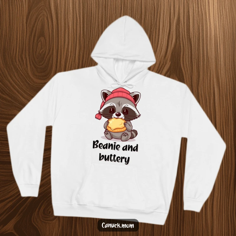 Funny raccoon in a beanie eating a butter tart, warm and humorous hoodie for snack lovers.