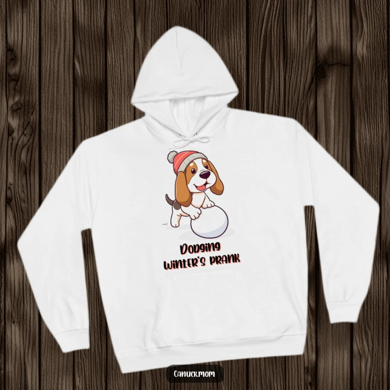 Funny Basset Hound Hoodie: A dog in a warm cap stumbles over a rolling snowball, full of humor.